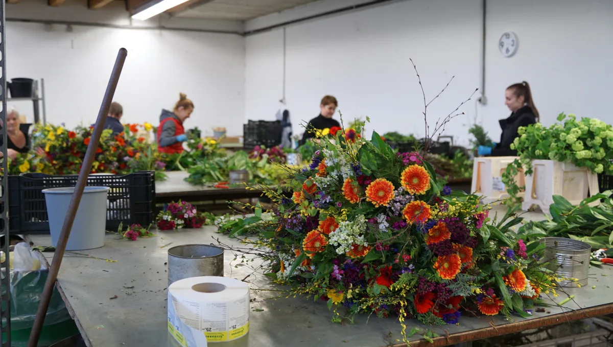 Blumenstrauss in einer Gärtnerei, im Hintergrund Floristinnen.